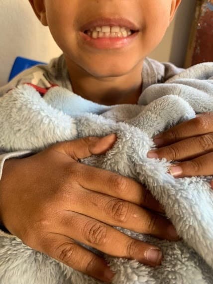 Criança acolhida com um cobertor durante uma ação da ACAI