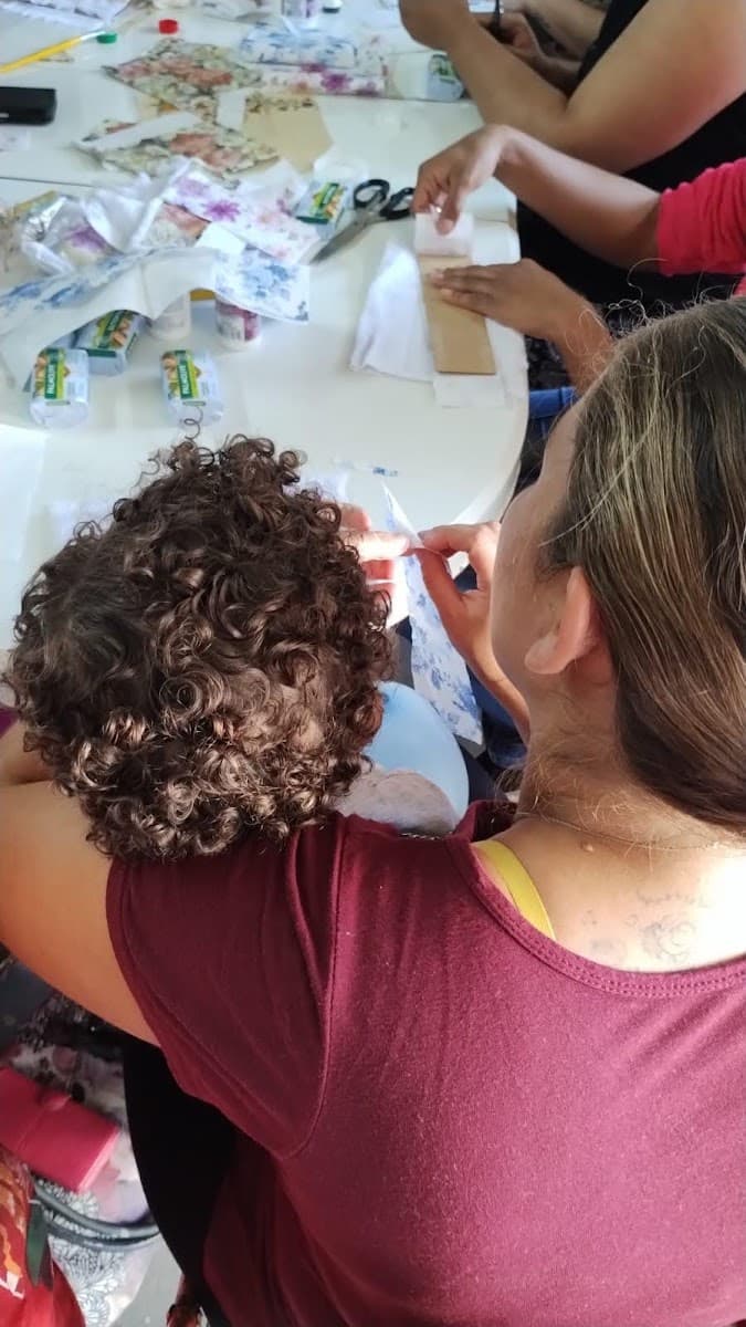 Família recebendo itens de cuidado durante encontro da ACAI — registro 008