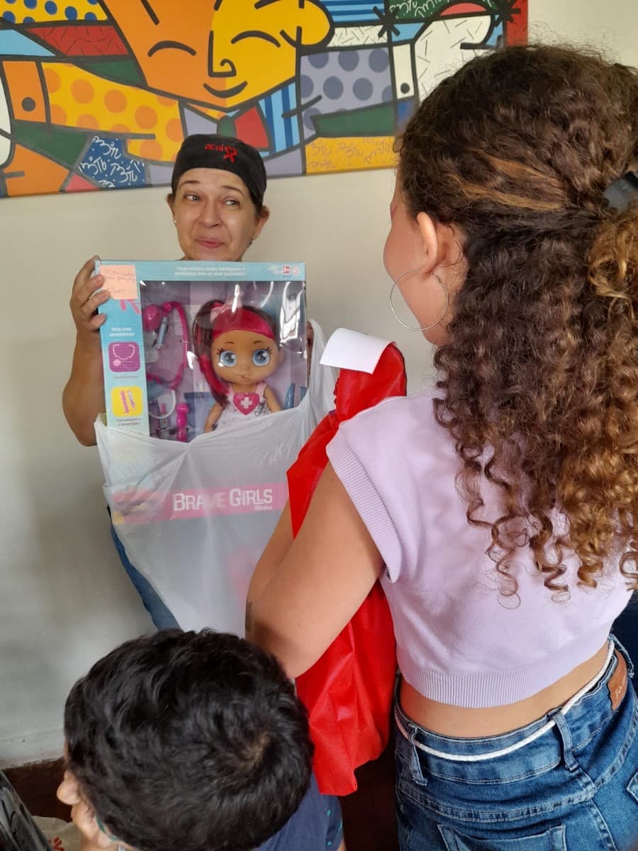 Família recebendo itens de cuidado durante encontro da ACAI — registro 018